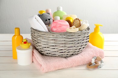 Photo of Wicker basket with baby cosmetics and accessories on white wooden table