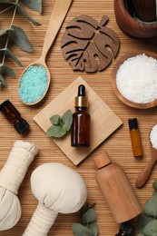 Photo of Different aromatherapy products and eucalyptus leaves on bamboo mat, flat lay