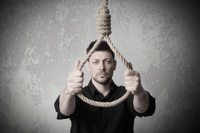 Depressed man with rope noose on light background. Suicide concept