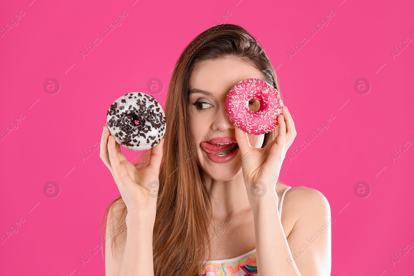 Photo of Beautiful young woman with donuts on pink background