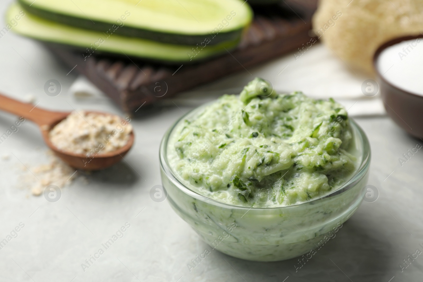 Photo of Handmade cucumber face mask in glass bowl on light grey table