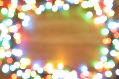 Blurred view of frame made with colorful Christmas lights on light background. Bokeh effect