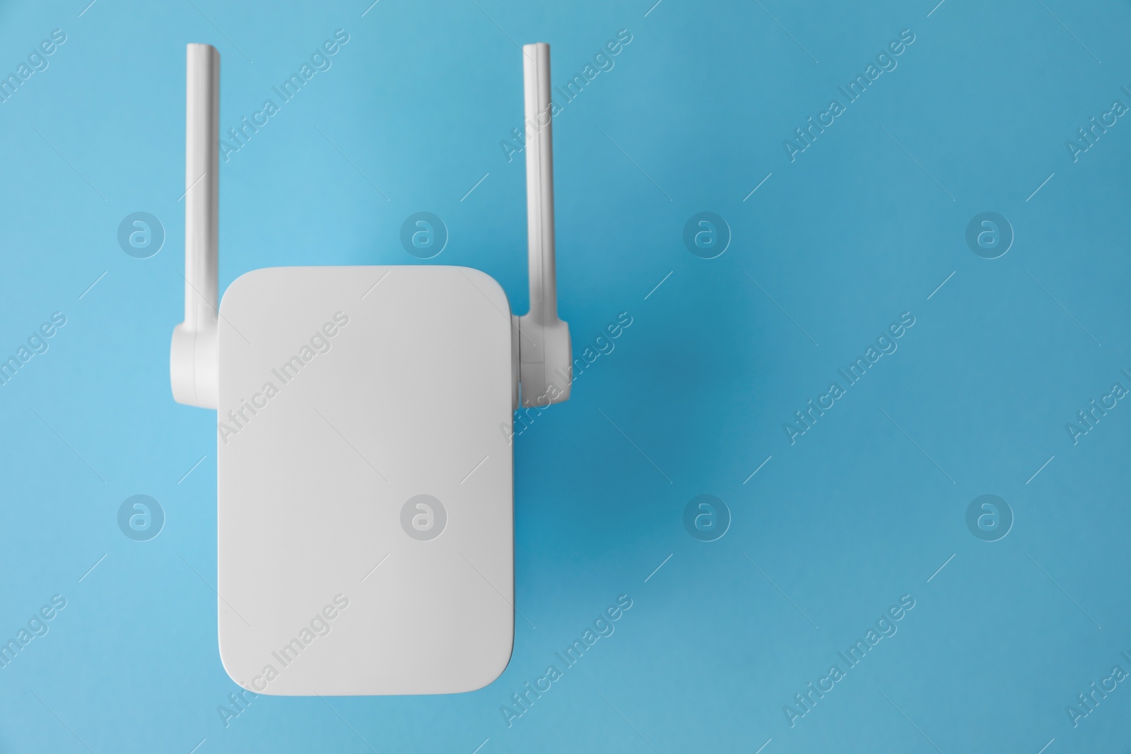 Photo of New modern Wi-Fi repeater on light blue background, top view. Space for text