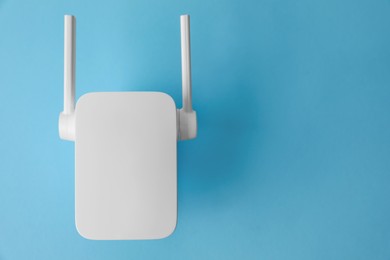 Photo of New modern Wi-Fi repeater on light blue background, top view. Space for text
