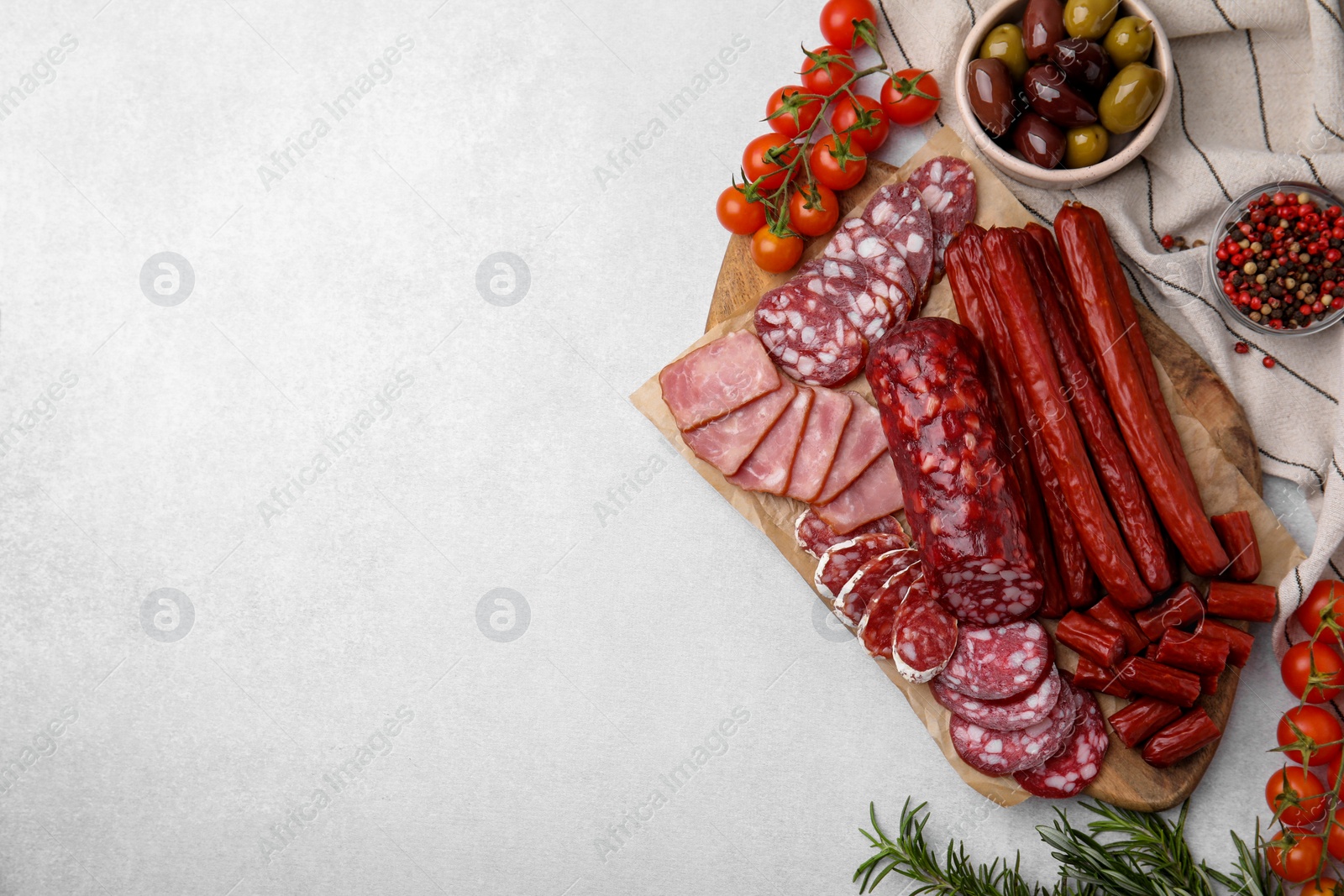 Photo of Flat lay composition with different types of delicious sausages and ingredients on light grey table. Space for text