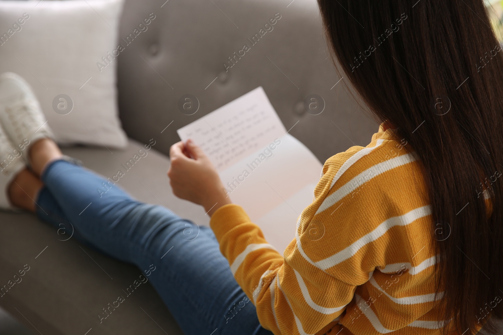 Photo of Woman reading letter on sofa at home, closeup