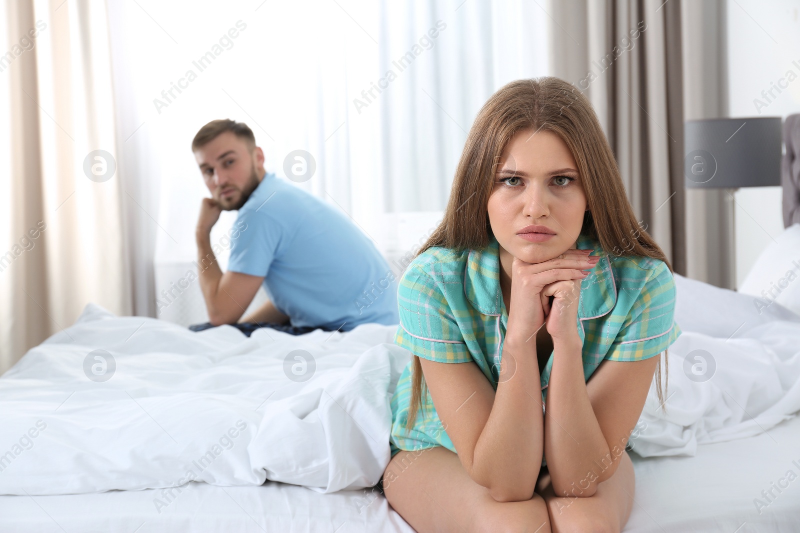 Photo of Young couple with relationship problems ignoring each other in bedroom