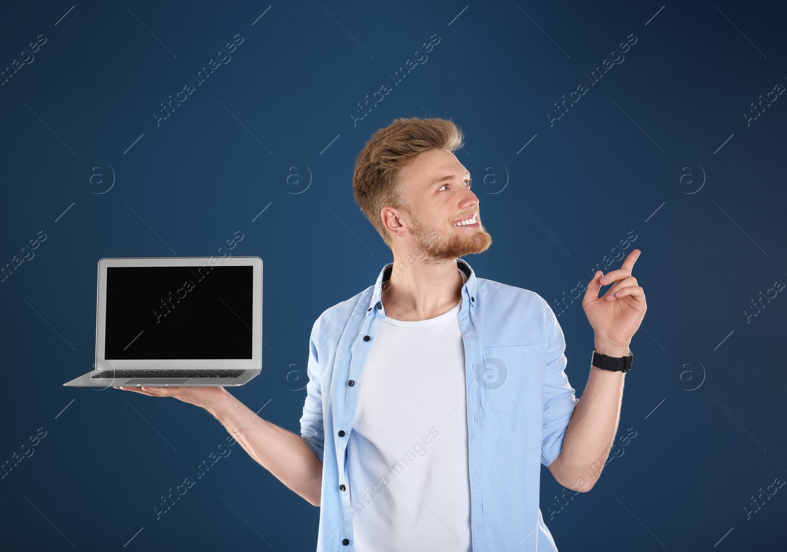 Photo of Happy man with laptop on blue background. Space for text