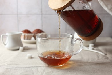 Photo of Pouring warm tea into cup on light table, closeup