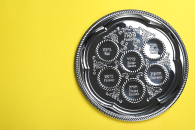 Photo of Passover Seder plate (keara) on yellow background, top view with space for text. Pesah celebration