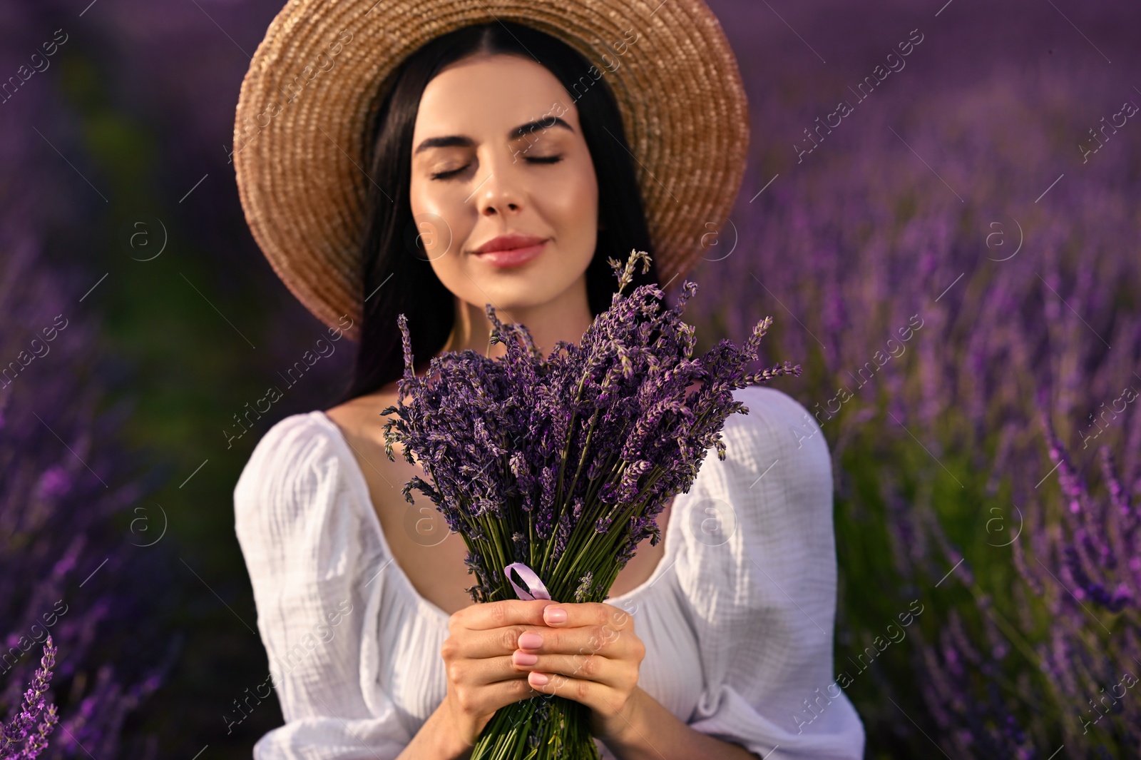 Photo of Beautiful young woman with bouquet in lavender field