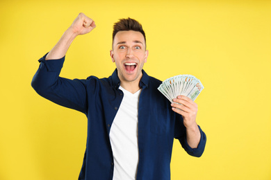 Photo of Emotional man with cash money on yellow background