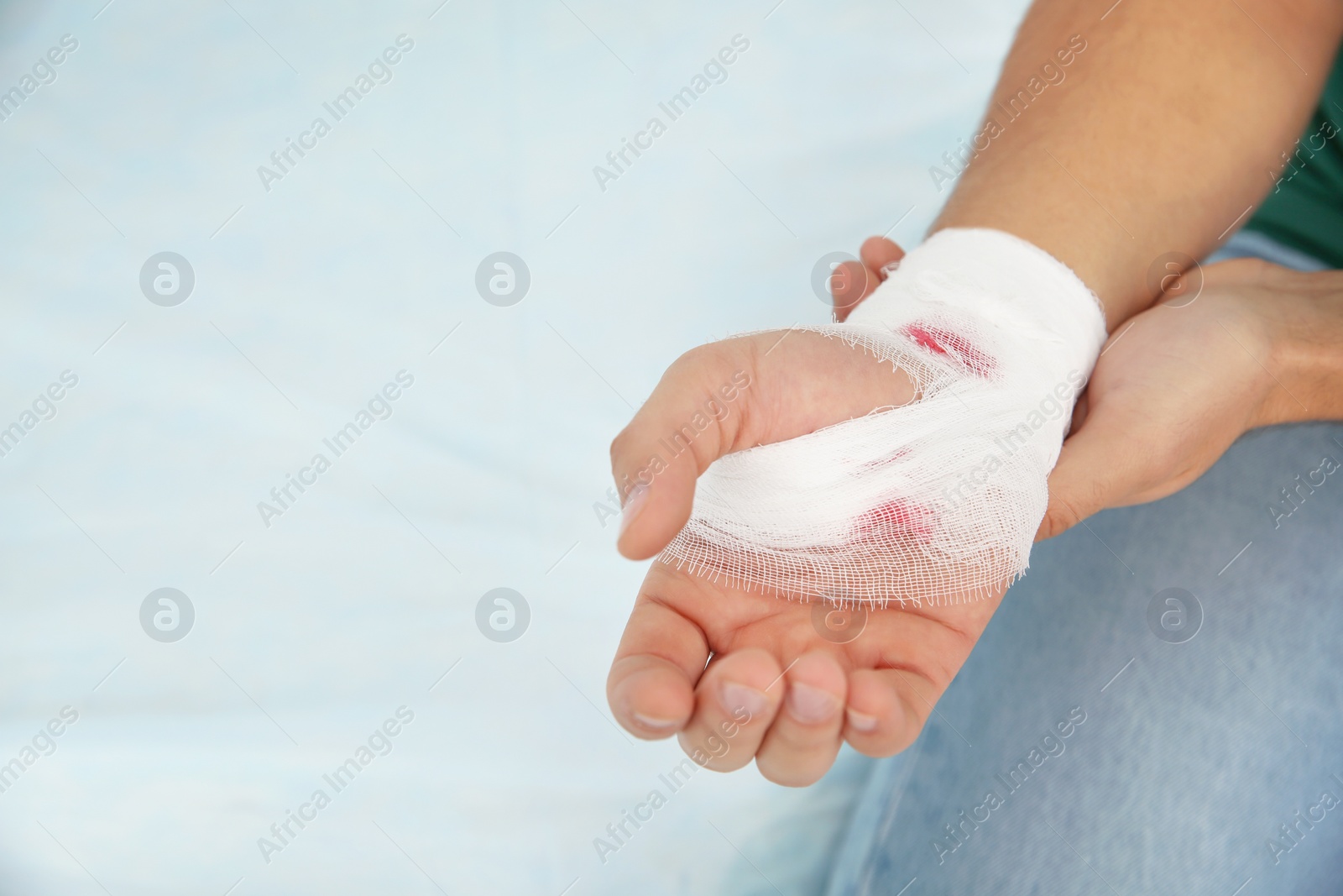 Photo of Young man with bandage on injured hand in clinic, space for text. First aid