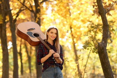 Teen girl with acoustic guitar in autumn park