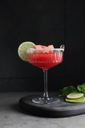 Photo of Cocktail glass of delicious fresh watermelon juice, lime and mint on grey table