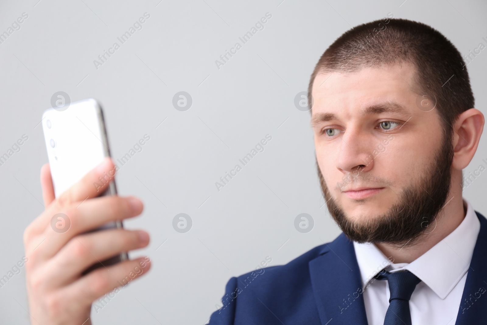 Photo of Man unlocking smartphone with facial scanner on light background. Biometric verification