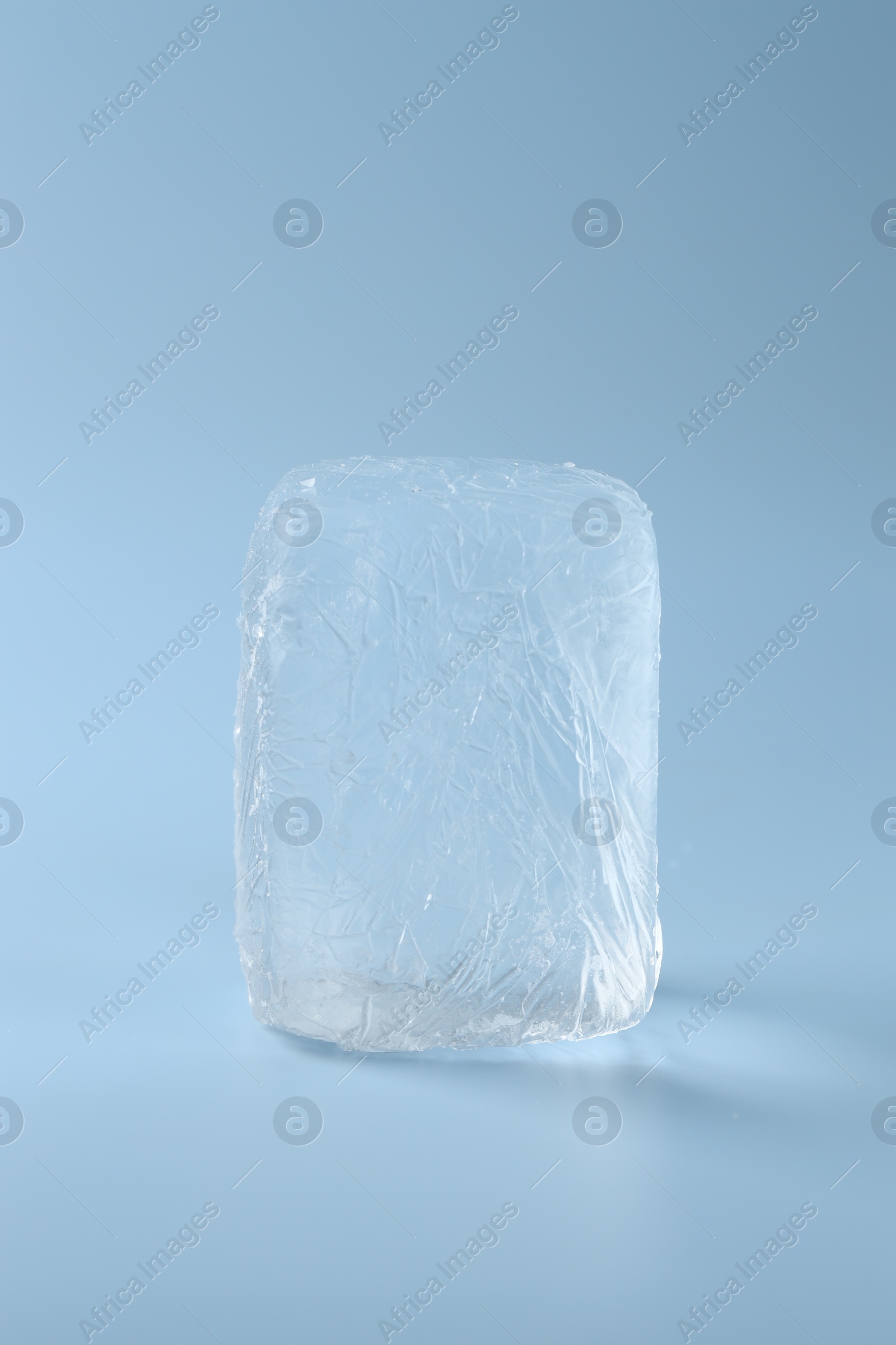 Photo of Block of clear ice on light blue background