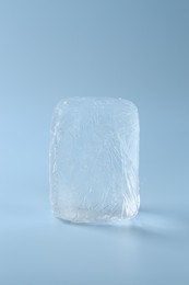 Block of clear ice on light blue background