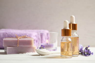 Photo of Composition with bottles of essential oil and lavender flowers on white wooden table