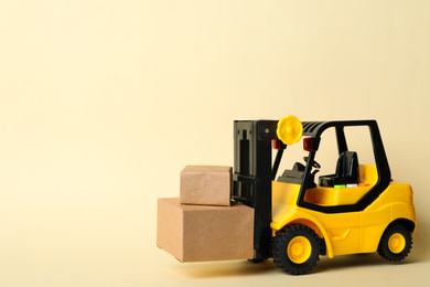 Toy forklift with boxes on beige background, space for text. Logistics and wholesale concept