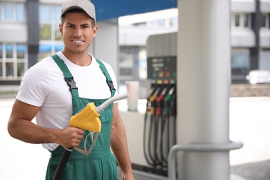 Photo of Worker with fuel pump nozzle at modern gas station