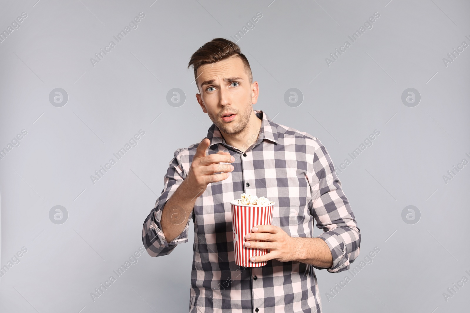 Photo of Emotional man with popcorn during cinema show on grey background