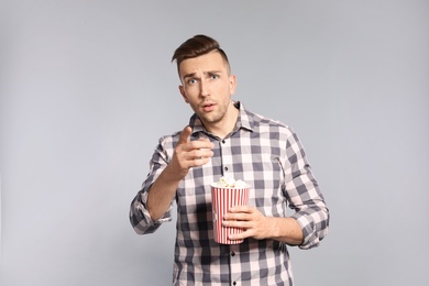 Photo of Emotional man with popcorn during cinema show on grey background