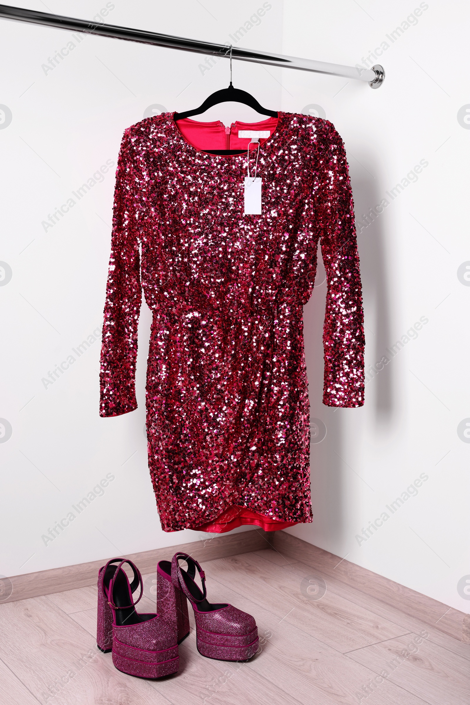 Photo of Beautiful pink women's party dress on hanger and punk square toe ankle strap pumps in showroom, space for text. Stylish trendy clothes for high school prom