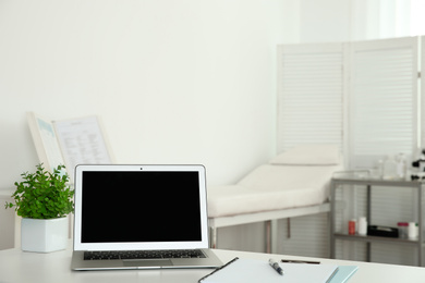 Photo of Modern laptop on desk in medical office, space for text. Doctor's workplace