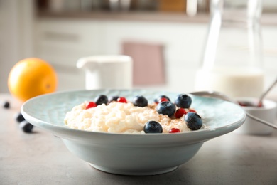 Photo of Creamy rice pudding with red currant and blueberries in bowl on table