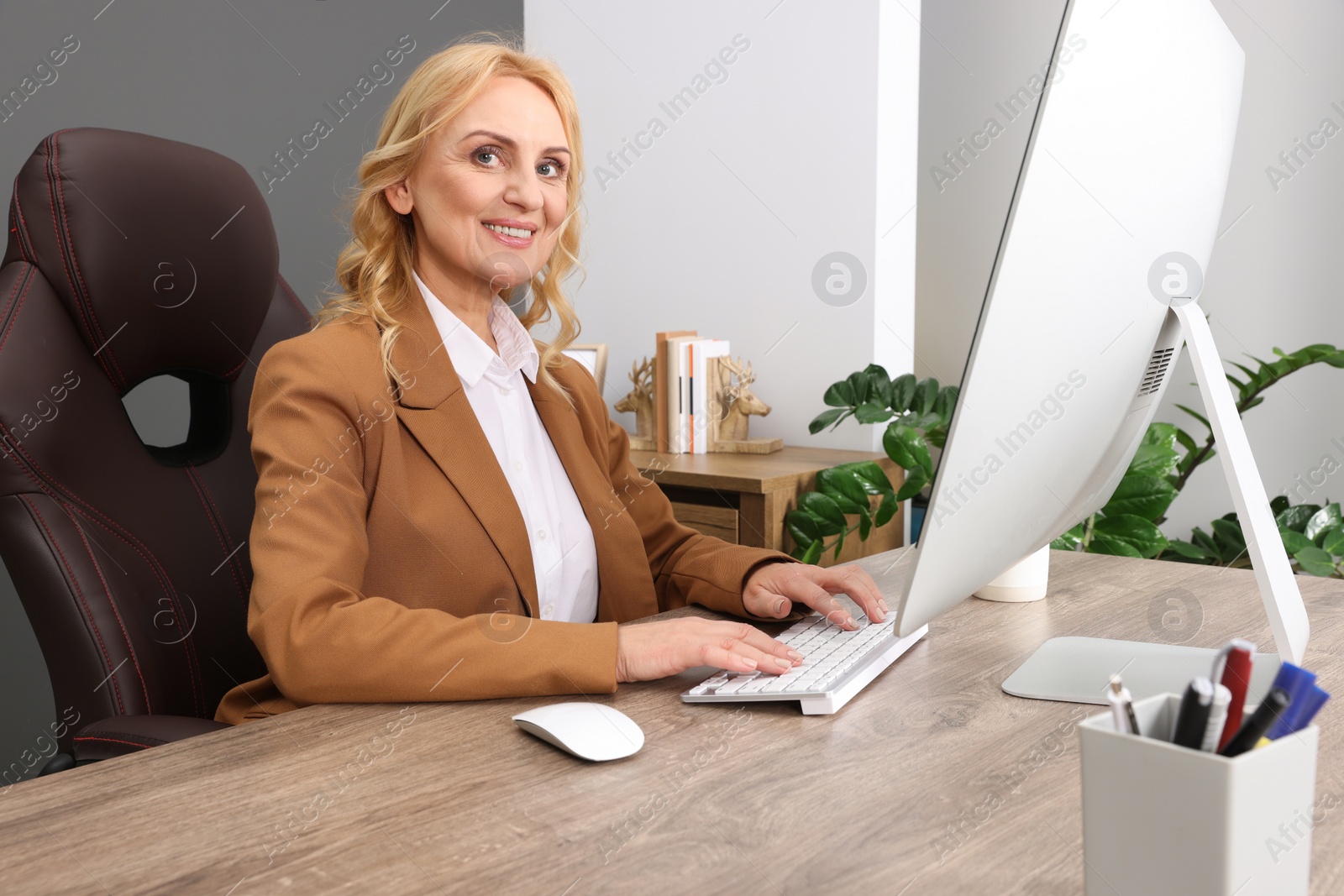 Photo of Lady boss working on computer at desk in office. Successful businesswoman