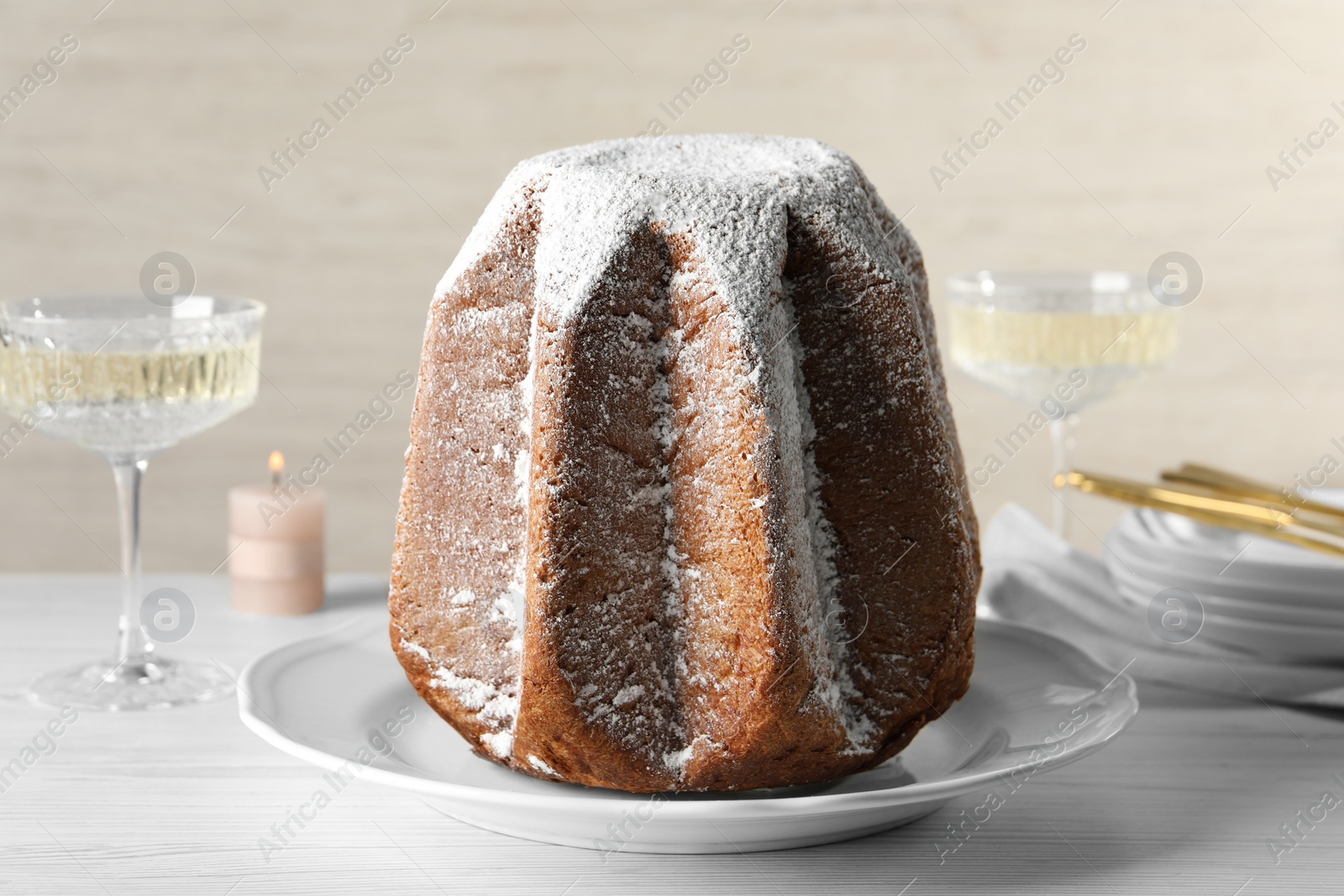 Photo of Delicious Pandoro cake decorated with powdered sugar and sparkling wine on white wooden table, closeup. Traditional Italian pastry