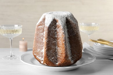 Photo of Delicious Pandoro cake decorated with powdered sugar and sparkling wine on white wooden table, closeup. Traditional Italian pastry