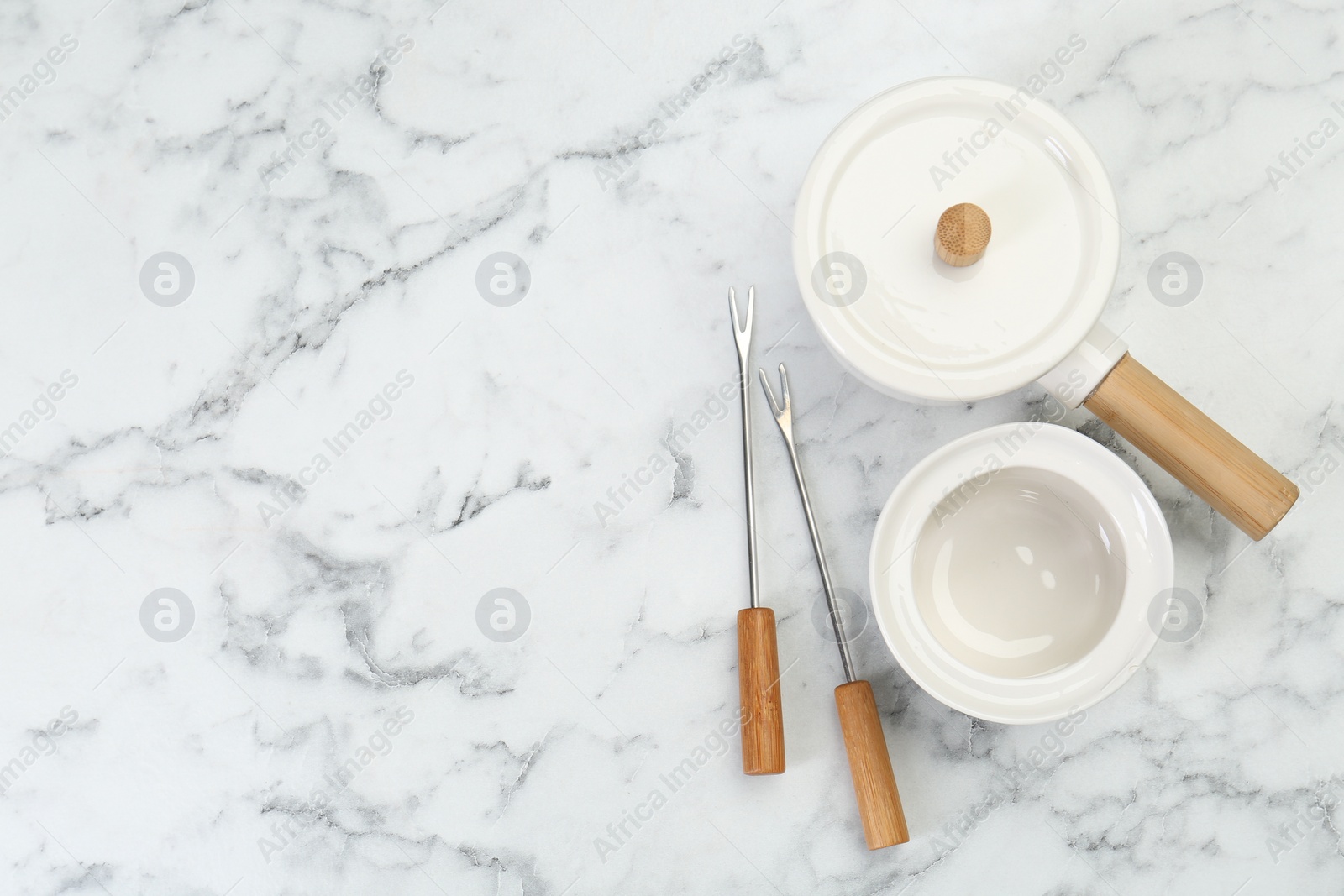 Photo of Fondue set on white marble table, flat lay. Space for text