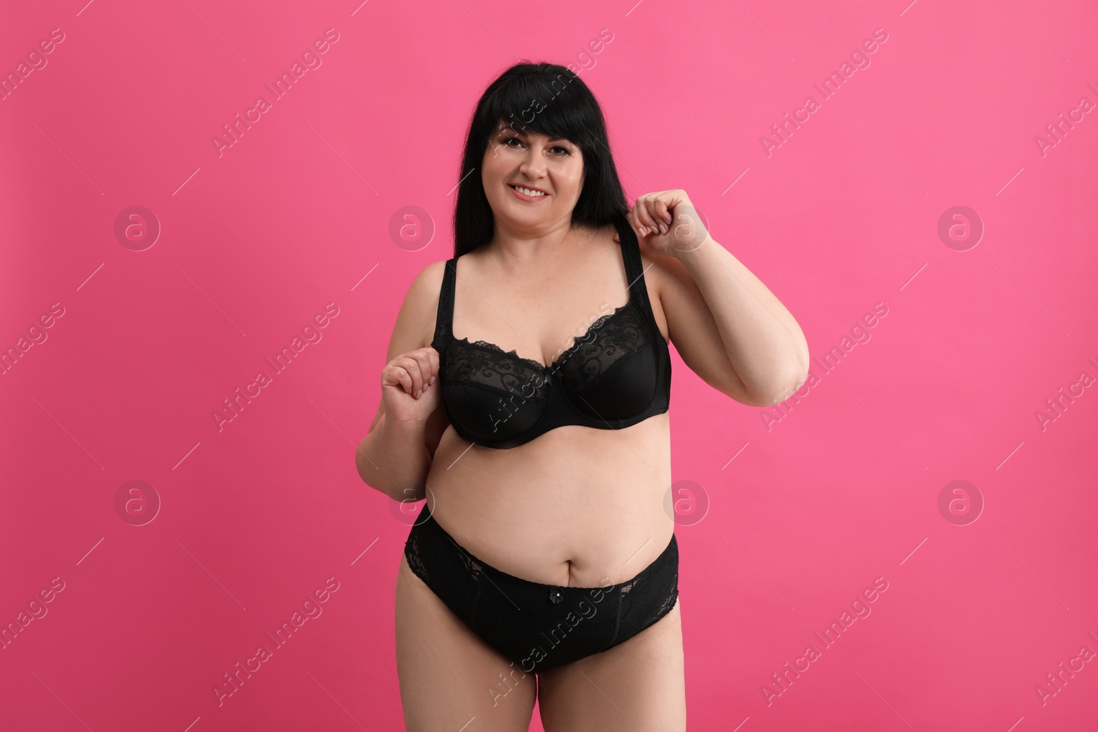 Photo of Beautiful overweight woman in black underwear on pink background. Plus-size model