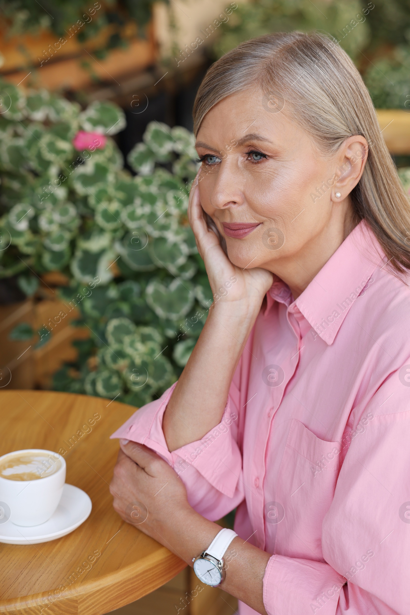 Photo of Portrait of beautiful senior woman with cup of coffee at table in outdoor cafe