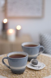 Photo of Cups of tea and snap infuser with dry leaves on table indoors, space for text