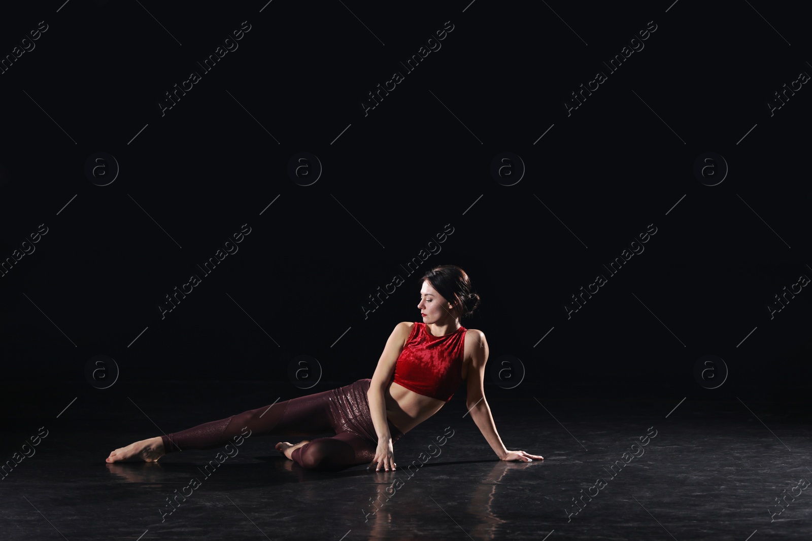 Photo of Young woman performing acrobatic element on stage indoors