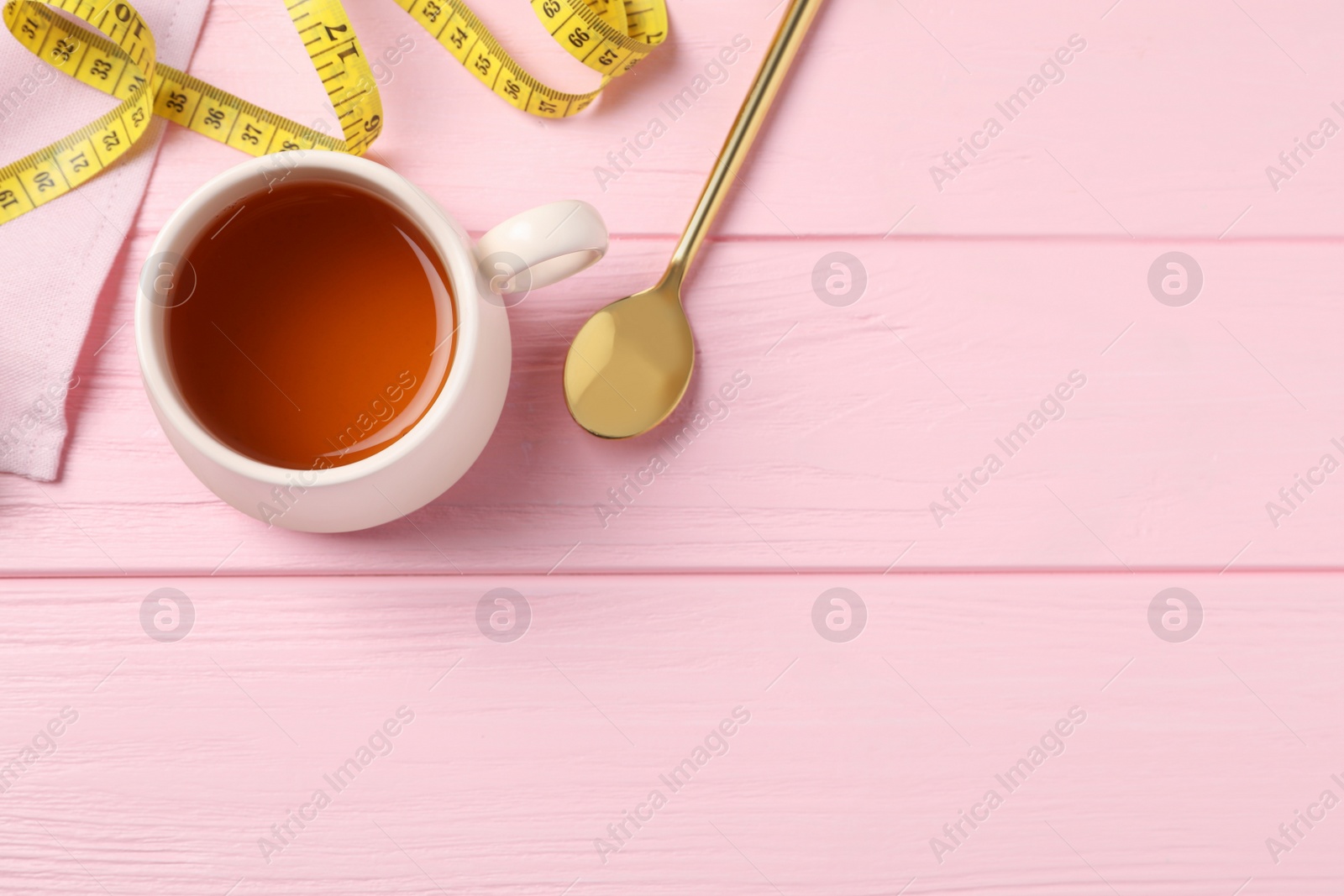 Photo of Flat lay composition with herbal diet tea and measuring tape on pink wooden table, space for text. Weight loss concept