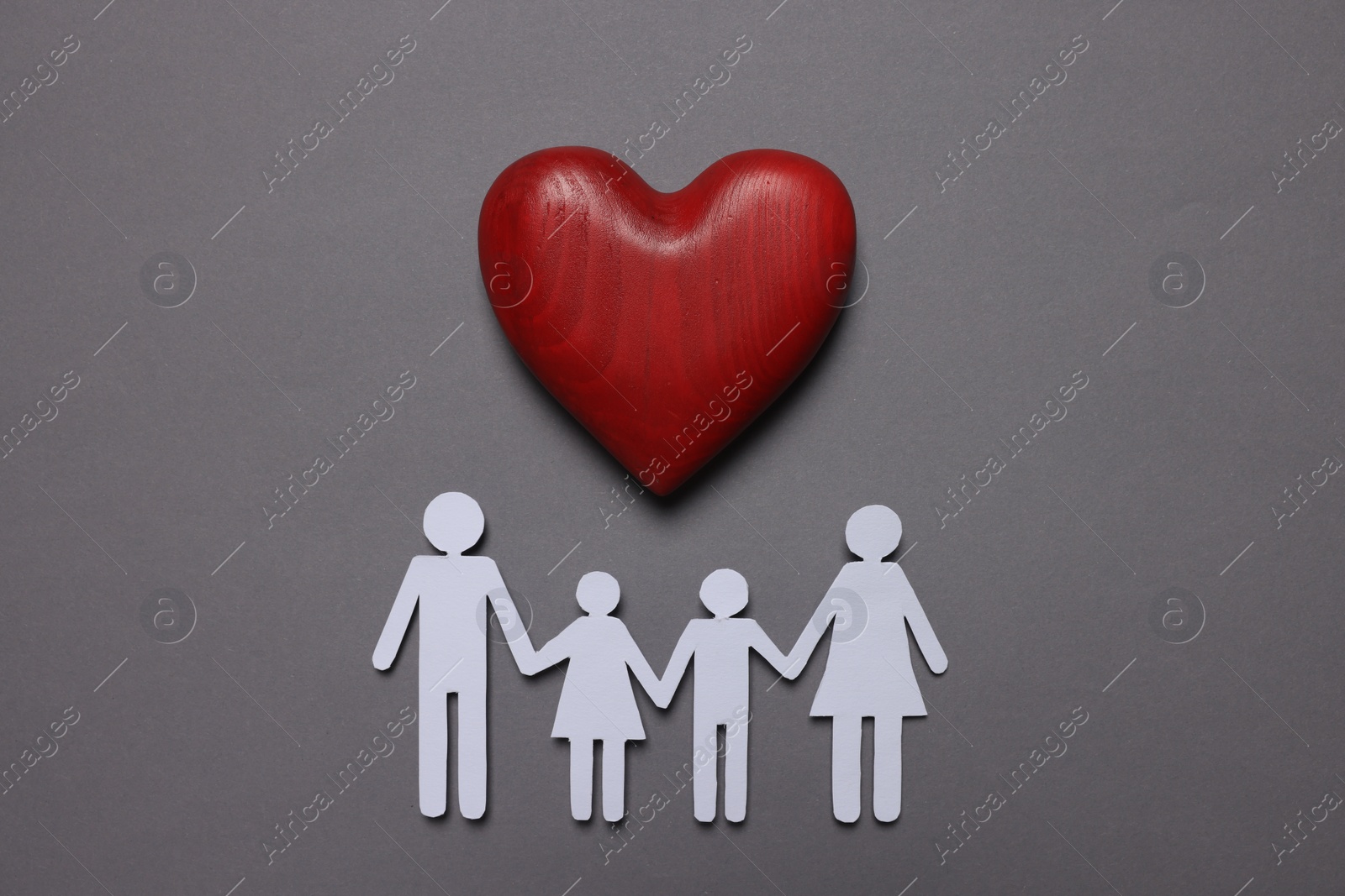 Photo of Paper family figures and red wooden heart on grey background, flat lay. Insurance concept