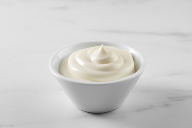 Photo of Tasty mayonnaise sauce in bowl on white table, closeup