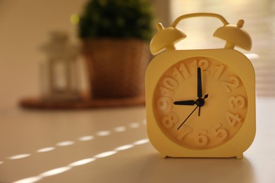 Photo of Yellow alarm clock on table indoors. Space for text