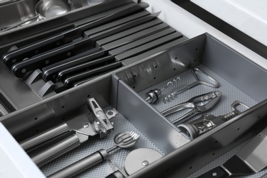 Open drawer with stainless steel utensil set, closeup. Order in kitchen