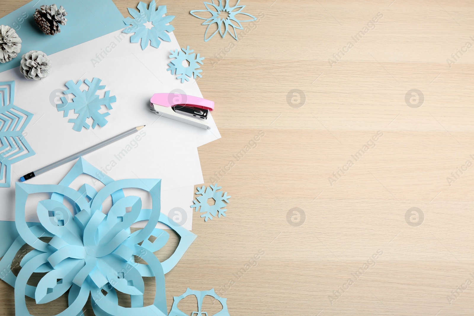 Photo of Flat lay composition with paper snowflakes on wooden table, flat lay. Space for text