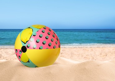 Image of Colorful beach ball on sandy coast near sea, space for text 