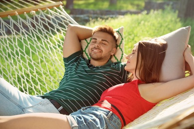 Young couple resting in comfortable hammock at green garden