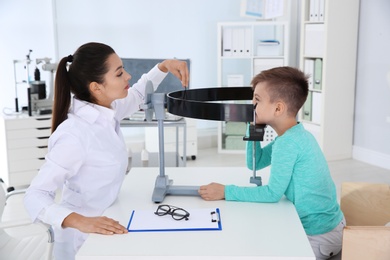 Photo of Children's doctor examining little boy's vision in clinic