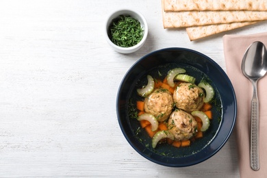 Flat lay composition with Jewish matzoh balls soup on white wooden table. Space for text