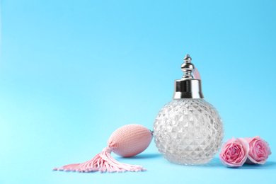 Photo of Bottle of perfume and flowers on light blue background