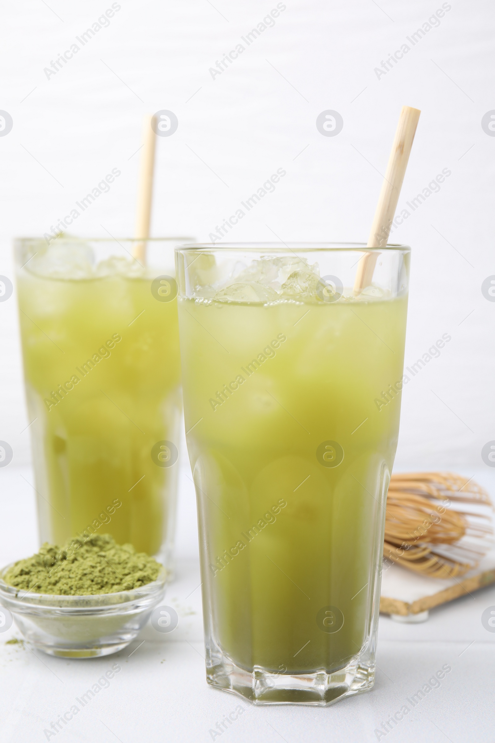 Photo of Delicious iced green matcha tea and powder on white table